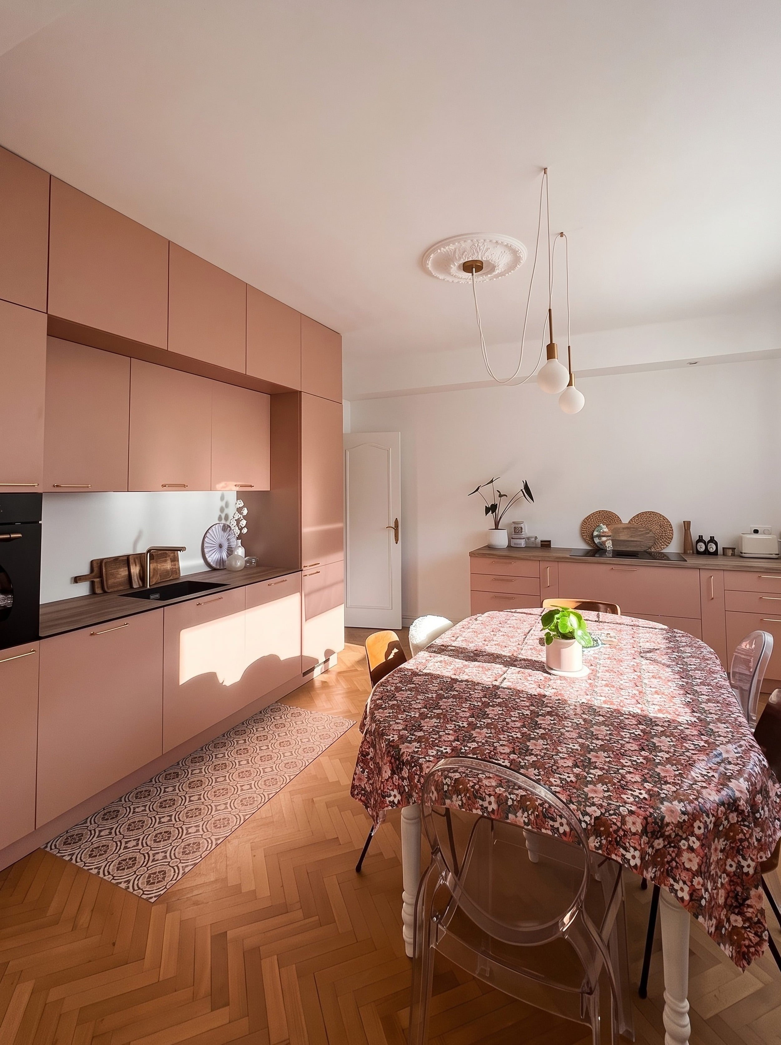 Cuisine aux façades abricot du sol au plafond, table à manger et parquet en chevrons