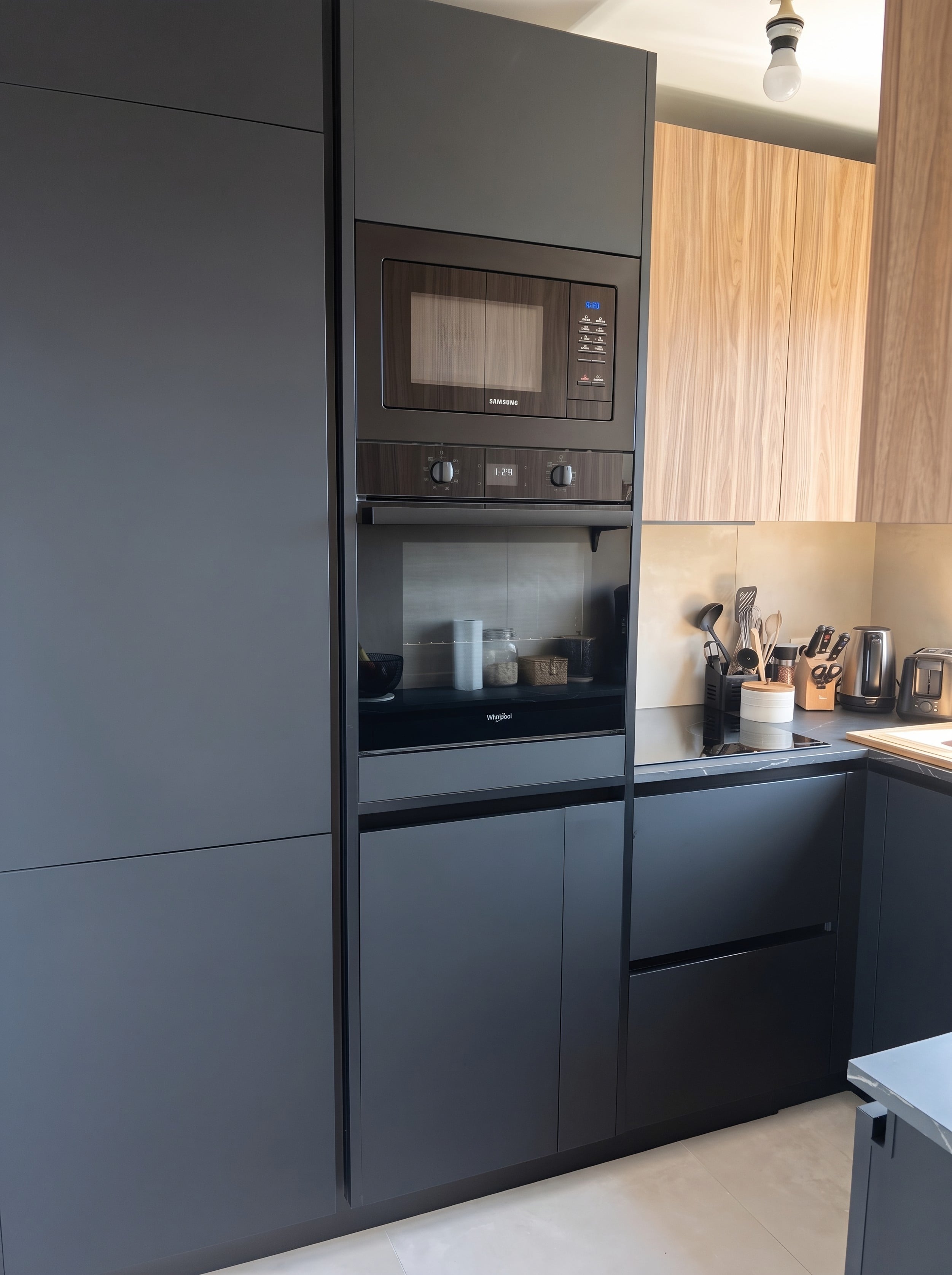 Colonnes anthracite mates sans poignées avec micro-ondes et four encastrés, meubles hauts en noyer