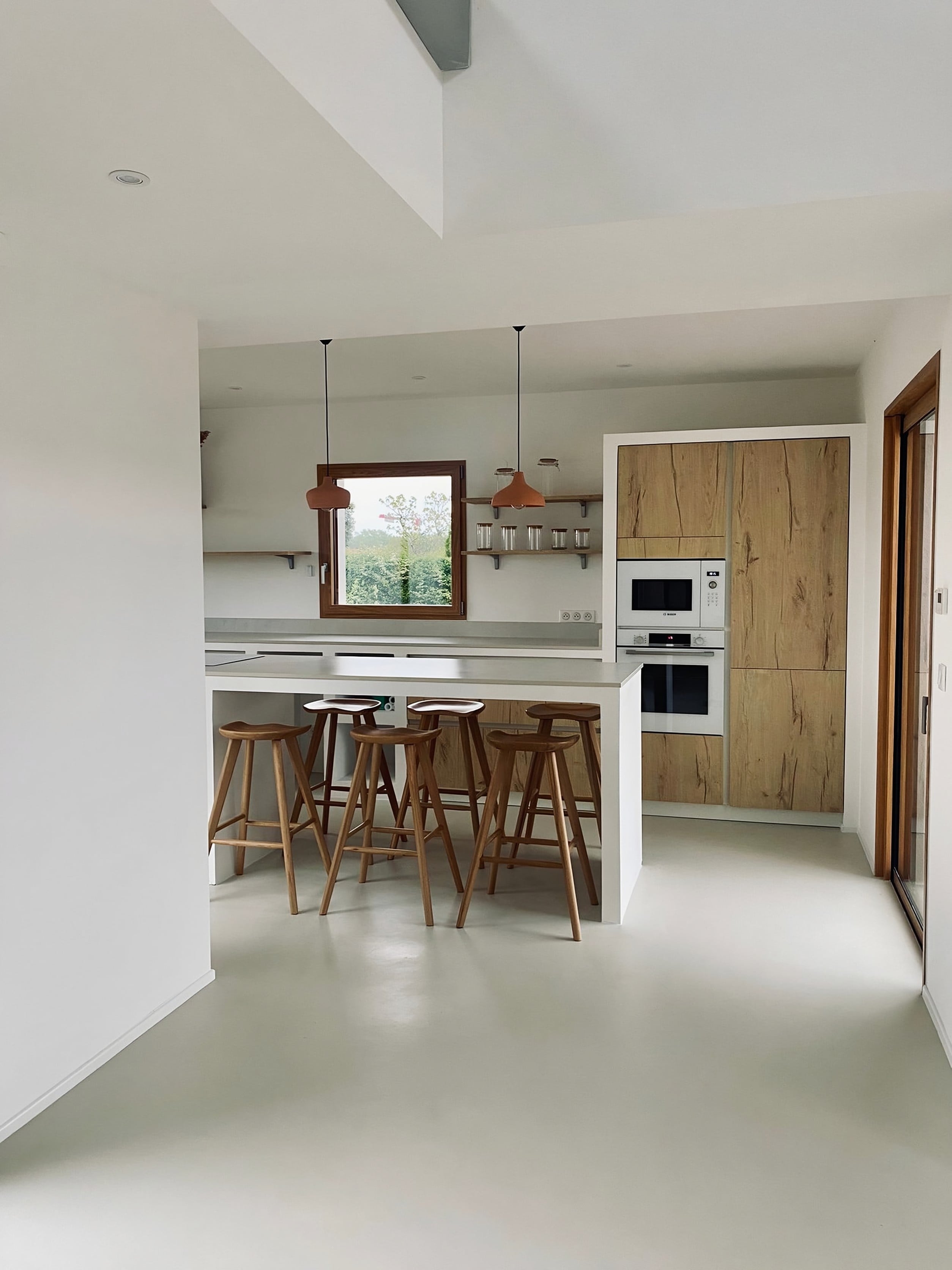 Vue d’ensemble de la cuisine au style maçonné : niches en plaques de plâtre, étagères et îlot blanc