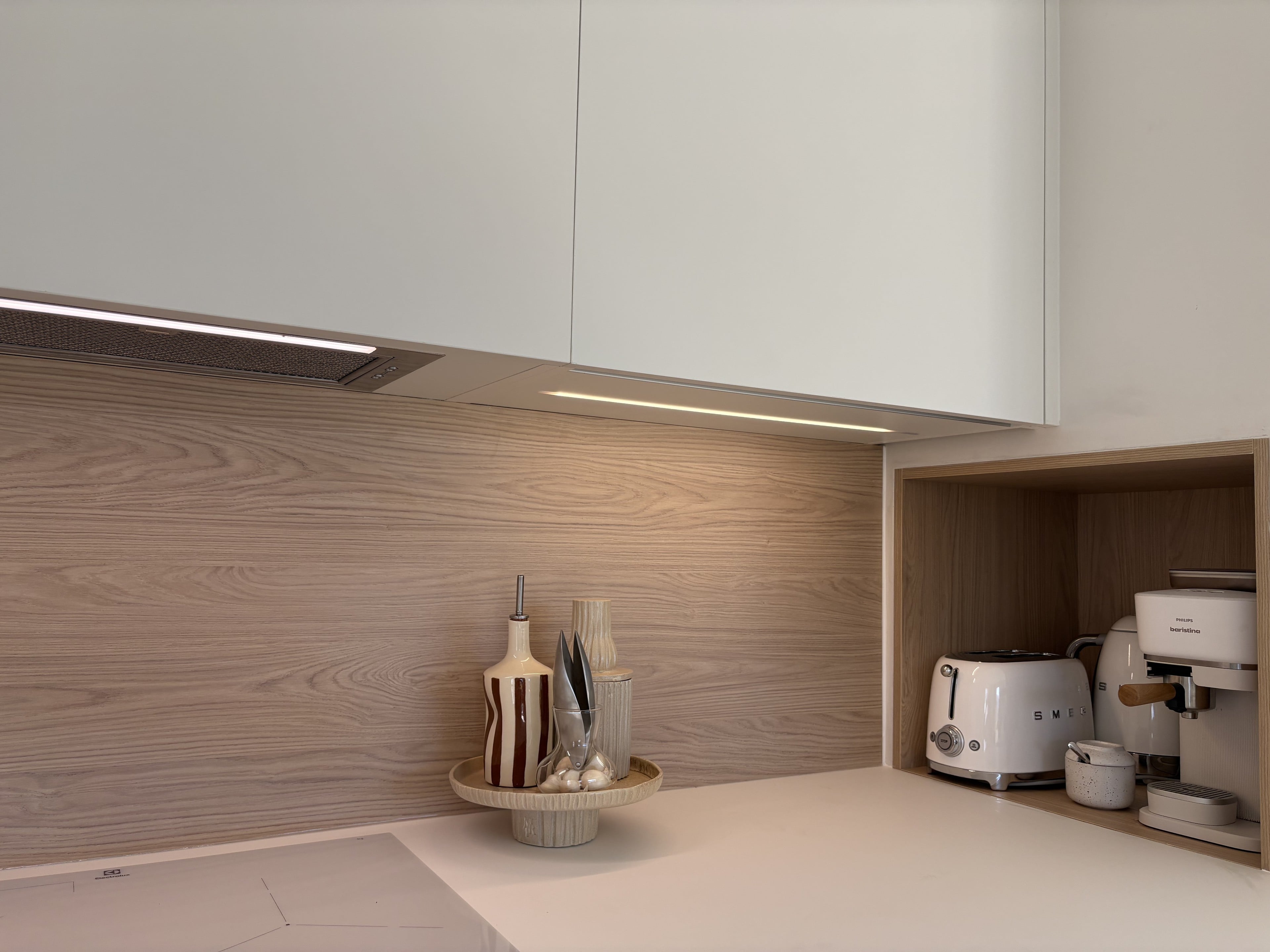 Crédence effet chêne d’un seul tenant, hotte intégrée sous le meuble haut et niche en bois pour les petits appareils