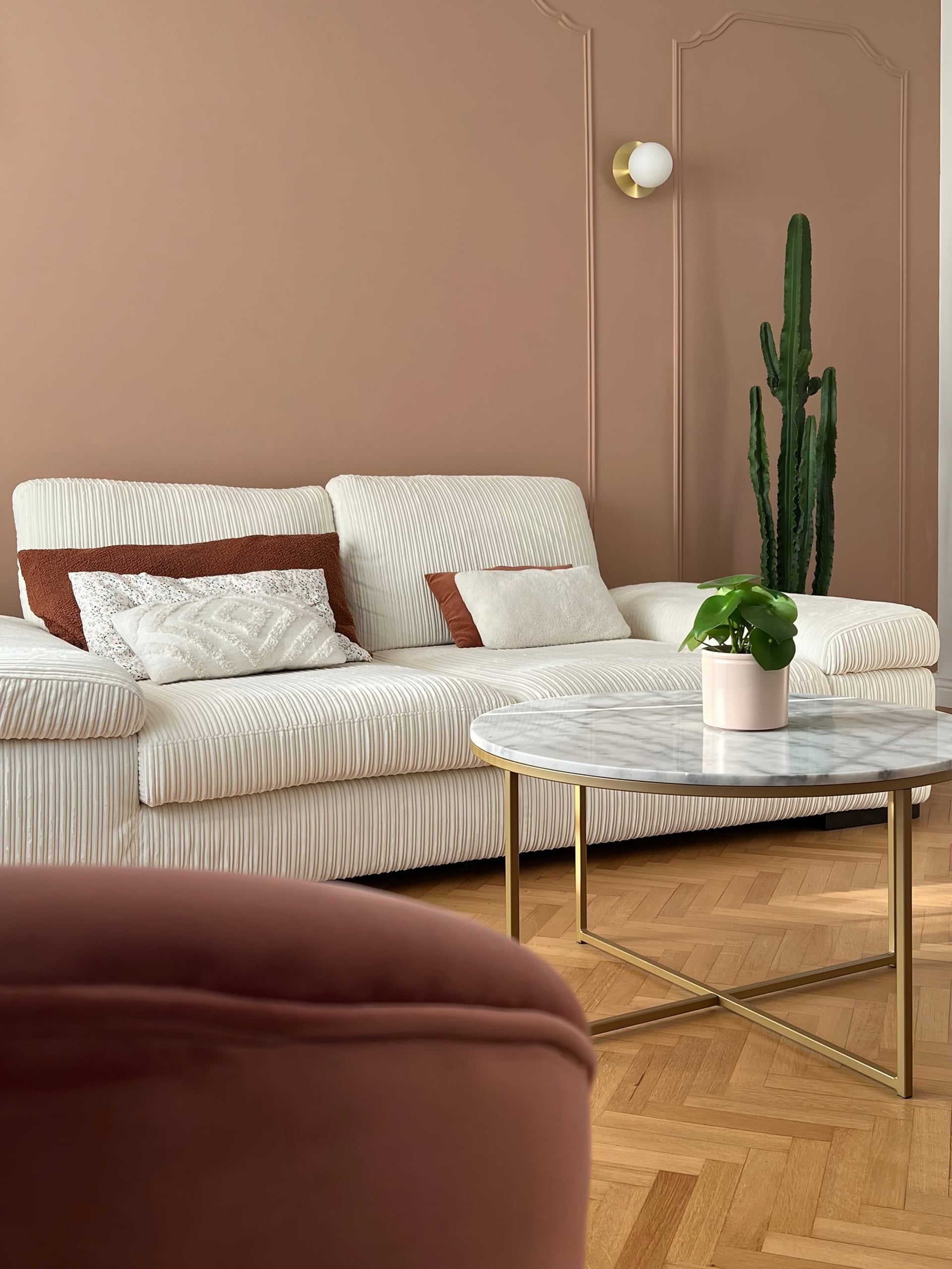 Salon au mur peint couleur abricot, canapé blanc et table basse en marbre
