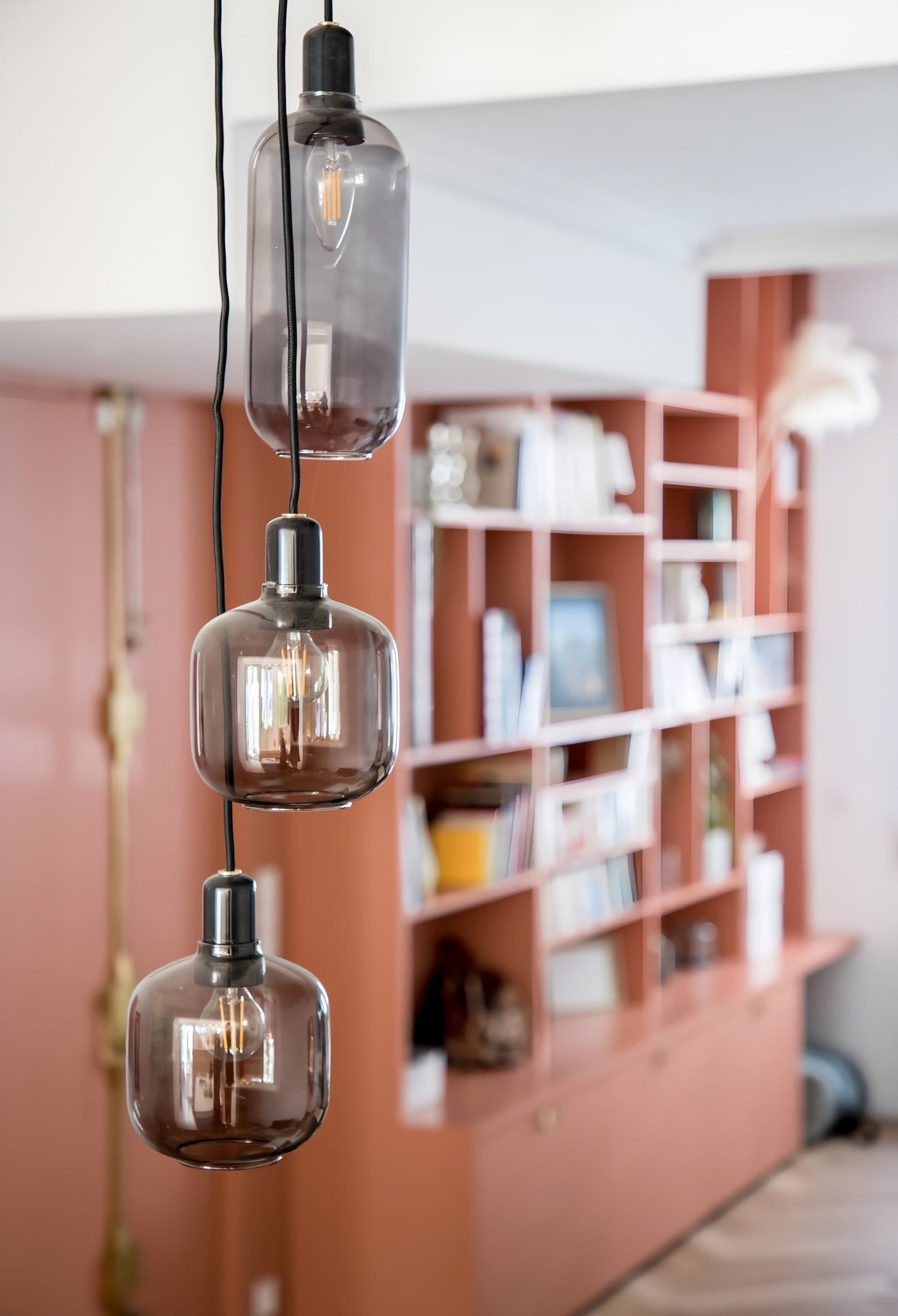 Bibliothèque terracotta toute hauteur et suspensions en verre ambré, projet de décoration de Julie Prats