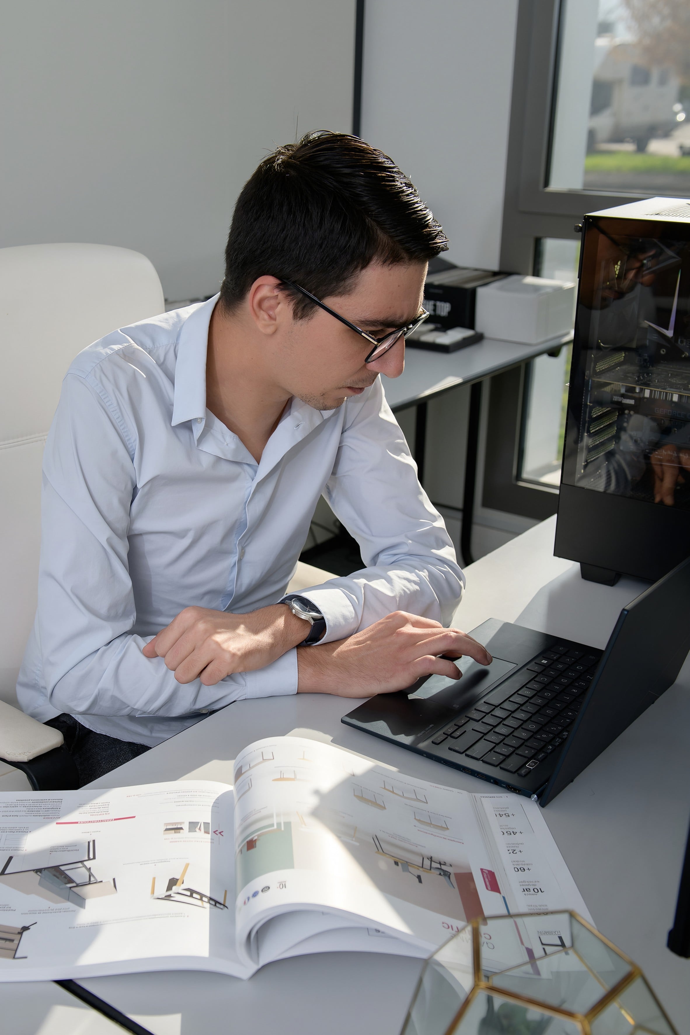 Clément Bouillaud, fondateur de Cuisin'Alp, travaillant sur un catalogue et un ordinateur portable à son bureau